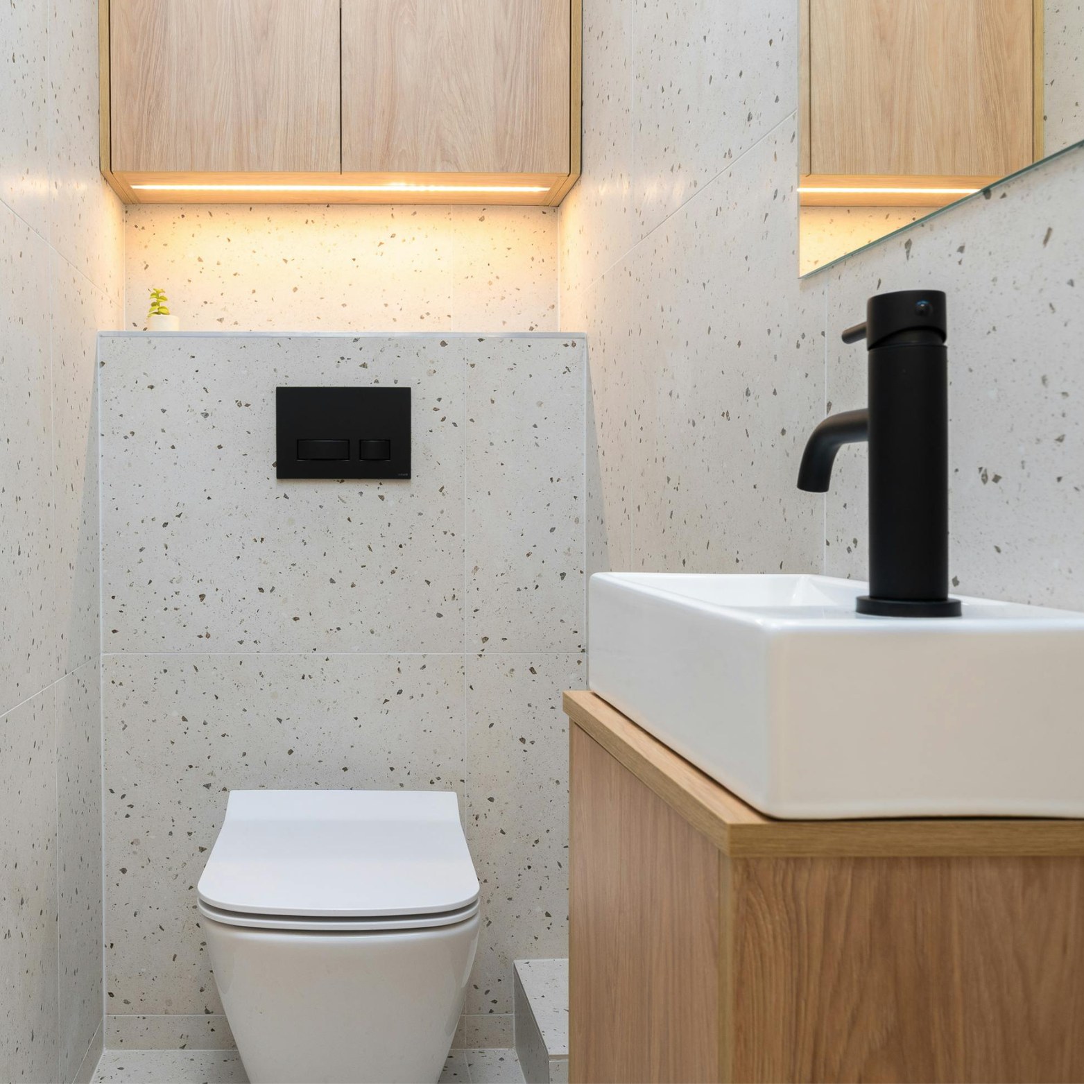 Toiletruimte met lichte tegels, houten meubels en zwarte kraan